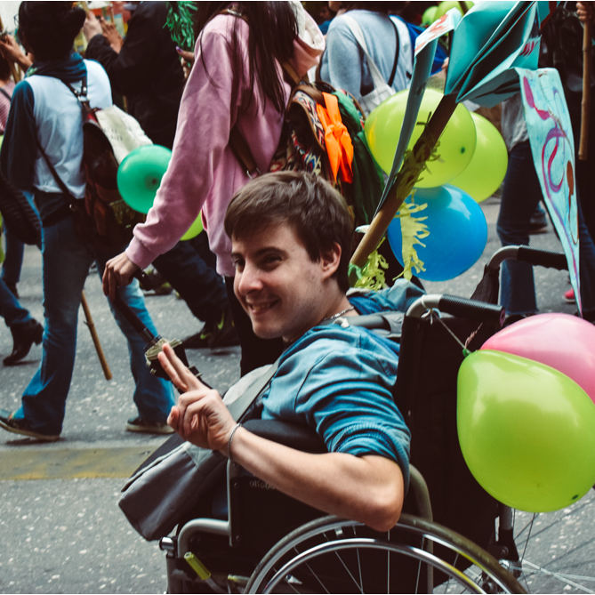 Foto del compa Maxi en la marcha. Se lo ve sonriente y levantando los dedos.