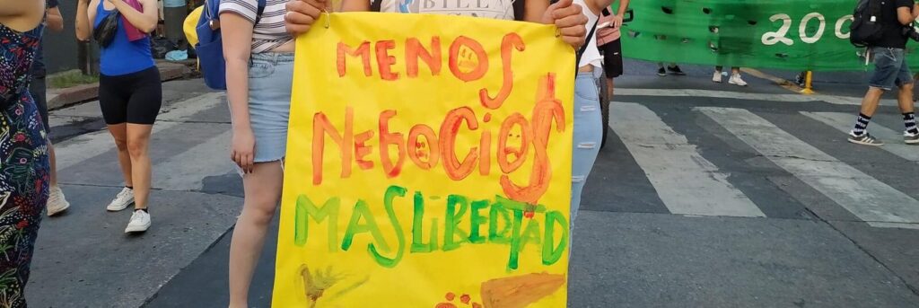 Un joven lleva un cartel que dice "menos negocios, más libertad" Marcha por el Derecho a la Salud Mental