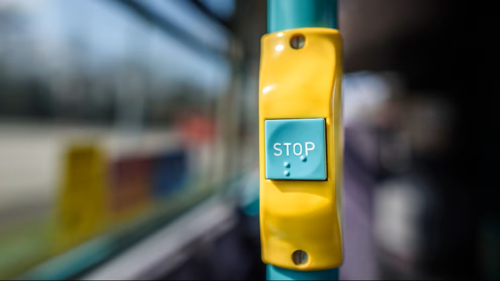 Botón de parar en un bus. Se lee Stop y en braille