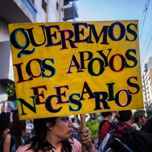 Foto de cartel llevado por una persona, se lee: "queremos los apoyos necesarios"